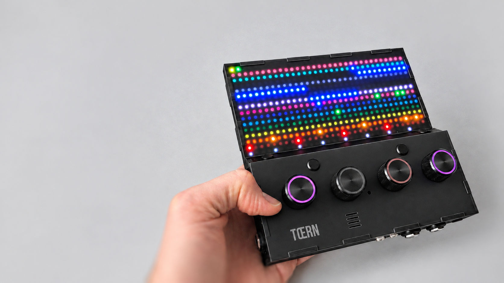Hand holding TŒRN with the LED grid lit